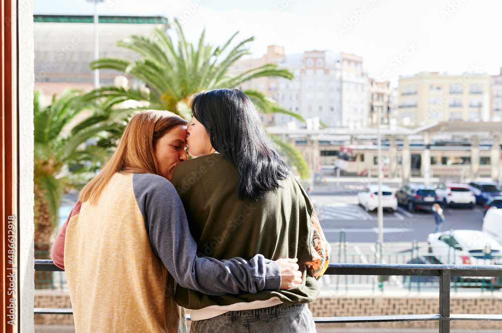 Loving lesbian couple standing on their balcony Loving lesbian couple standing on their balcony