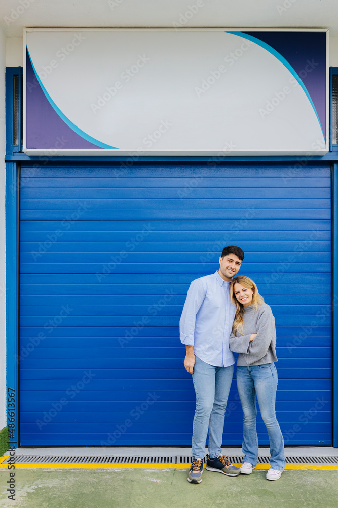 Cheerful couple standing on street near storage room door Cheerful couple standing on street near storage room door