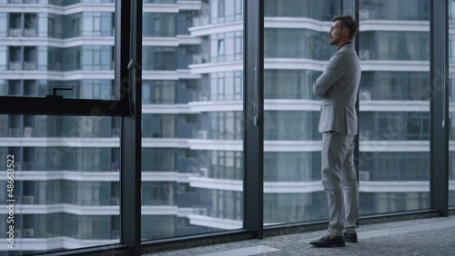 Successful man crossing hands looking window in business office building centre. photo