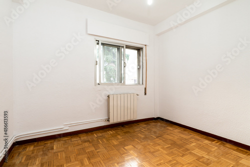 Empty room with white aluminum radiator with parquet floors and double aluminum window