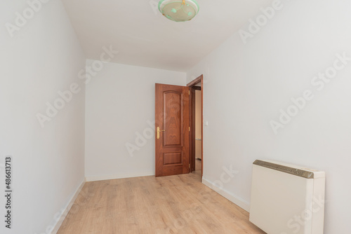 empty room with light wood floors, mahogany woodwork on the doors, electric storage radiator © Toyakisfoto.photos