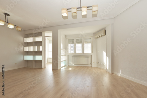 Living room with white work shelving, aluminum radiators, white lamps and air conditioning unit on the wall
