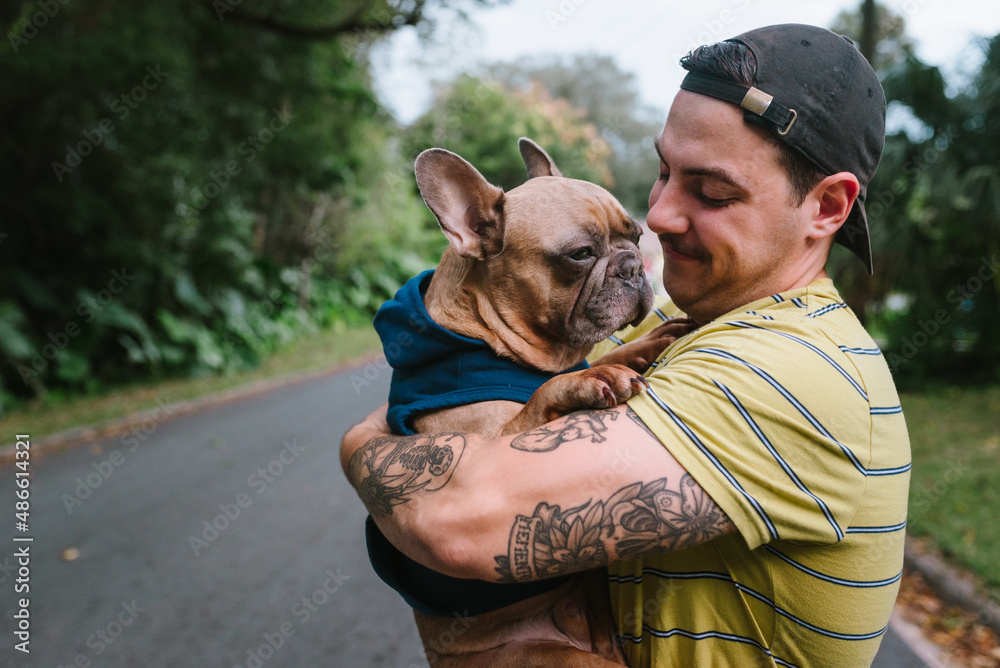 Tattooed man cuddling with Frenchie Tattooed man cuddling with Frenchie