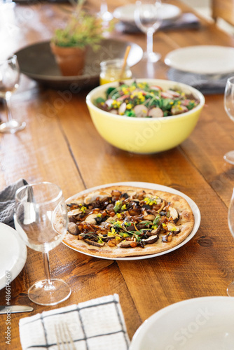 Vegetable flatbread and a garden salad on a rustic wooden table.