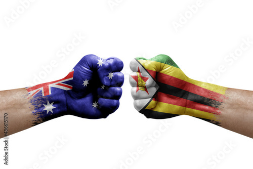 Two hands punch to each others on white background. Country flags painted fists, conflict crisis concept between australia and zimbabwe