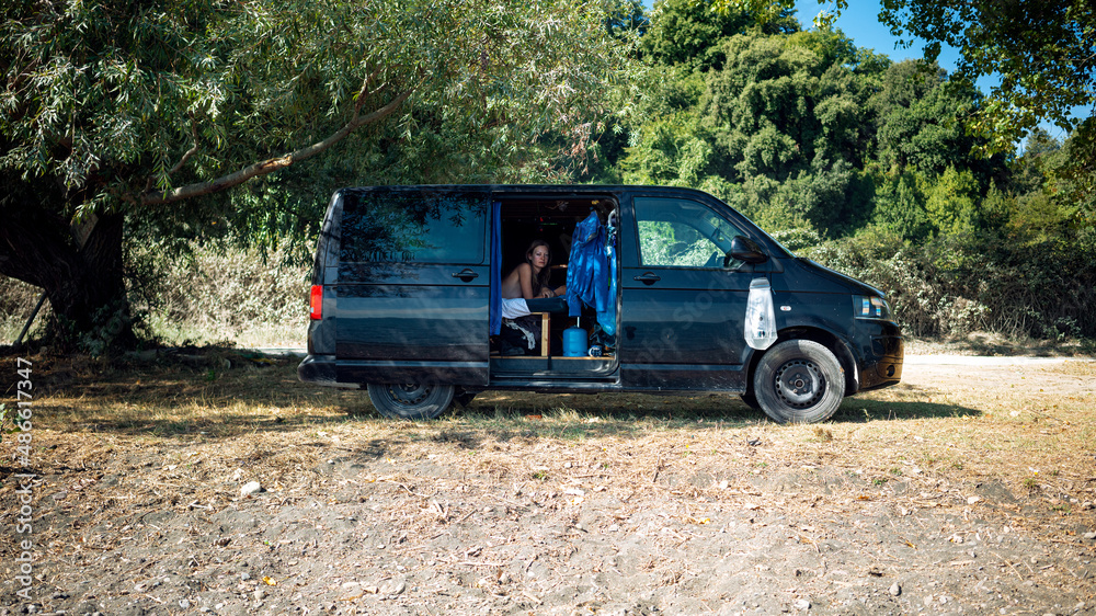 Beautiful girl camping in a cool camper van by the shore Beautiful girl camping in a cool camper van by the shore