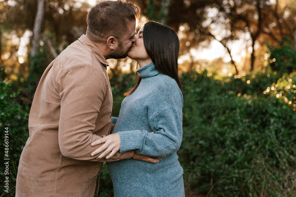 Loving husband kissing pregnant wife in nature Loving husband kissing pregnant wife in nature