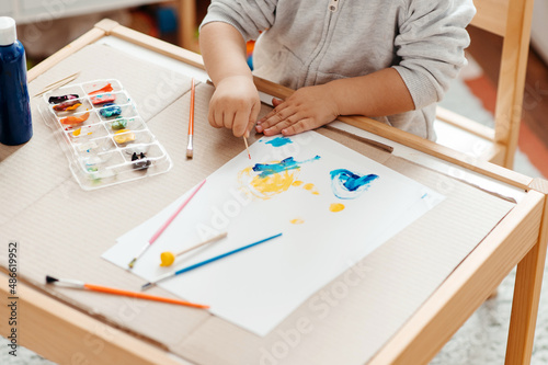 Crop kid painting on paper