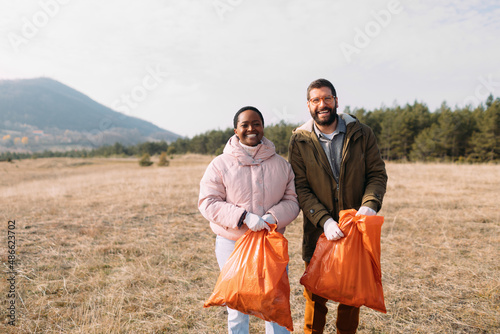 Man and Woman Collecting Garbage in Nature  photo
