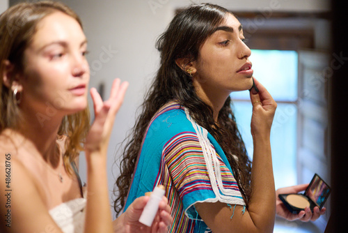 Relaxed females applying makeup in bathroom