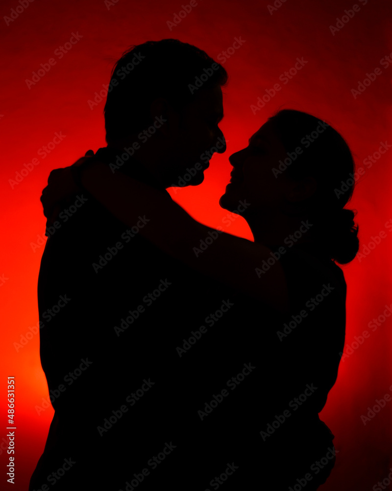 A silhoutte of a couple with red background