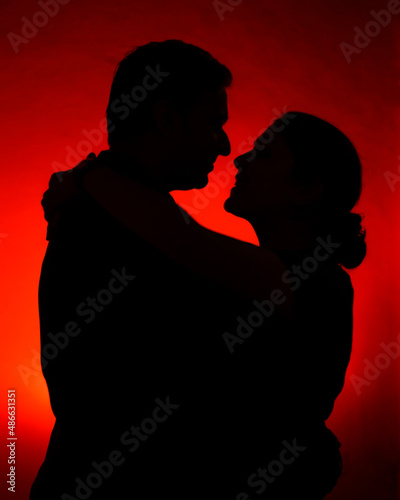 A silhoutte of a couple with red background