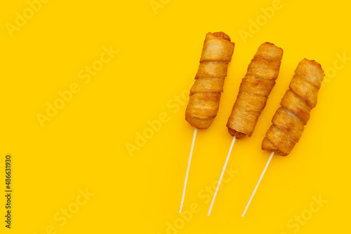 Fried dough snacks wrapped sausage on yellow background.
