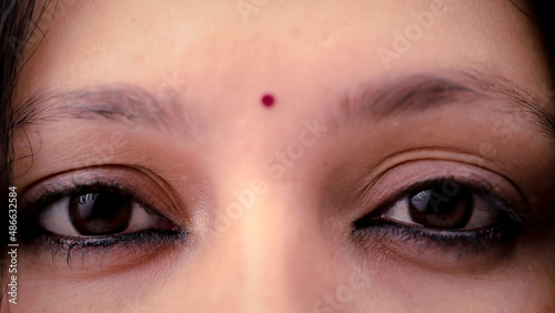 The eyes of an Indian lady with a red bindi on the forehead photo