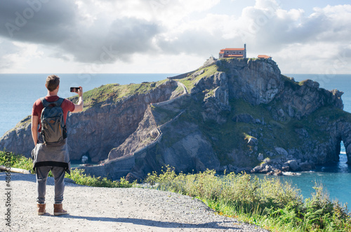 Male hiker photographing rocky islet at seaside