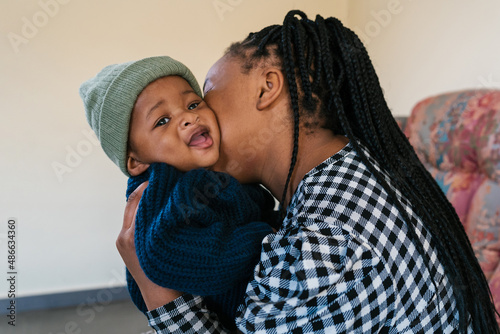 Black mother kissing cute toddler
