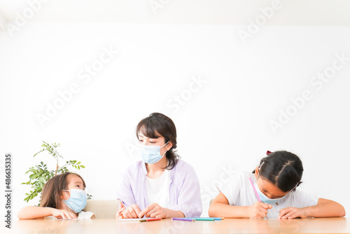 マスクを付けて勉強をする子供と塾講師