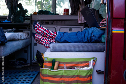 Young man with funky socks working on a laptop in his Campervan  photo