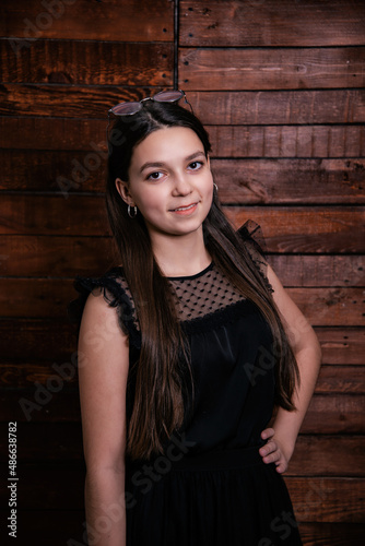 Cute portrait of a girl on a wooden background. Emotional child in a dress.