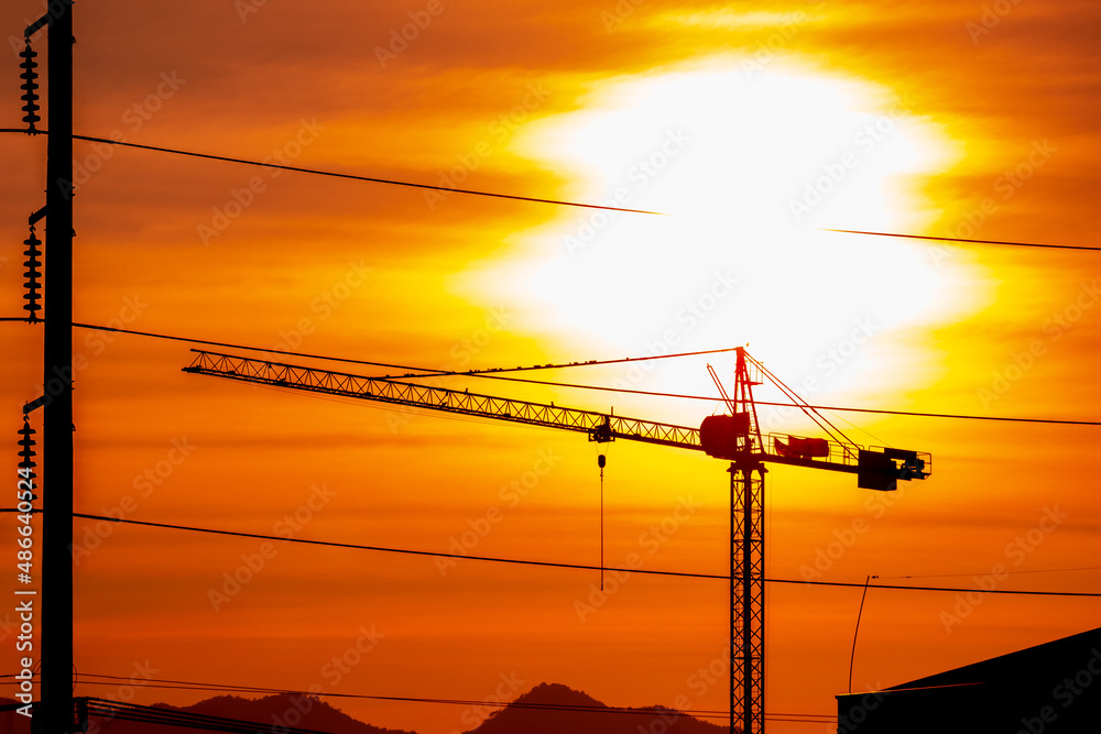 Silhouette building construction crane near the high voltage cable during sunset. construction site with crane at sunset