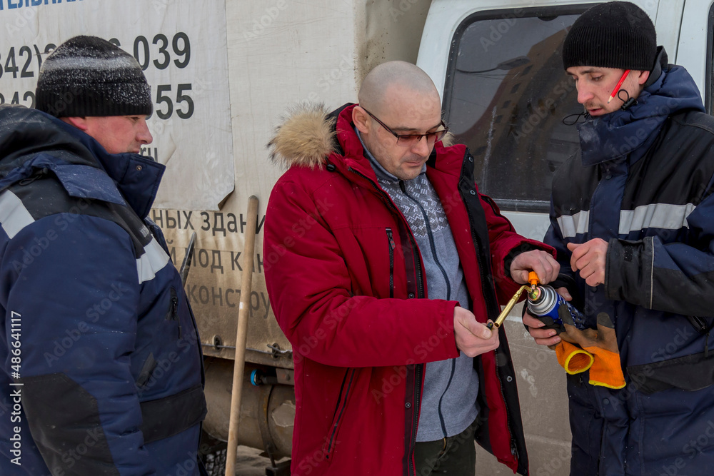 Three workers set up a gas burner Three workers set up a gas burner