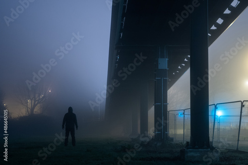 A man standing under a bridge at night