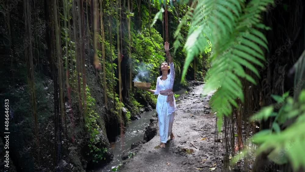 Divine woman walking in the tropical jungle along the brook, meditating contemplation, burning incenses Divine woman walking in the tropical jungle along the brook, meditating contemplation, burning incenses