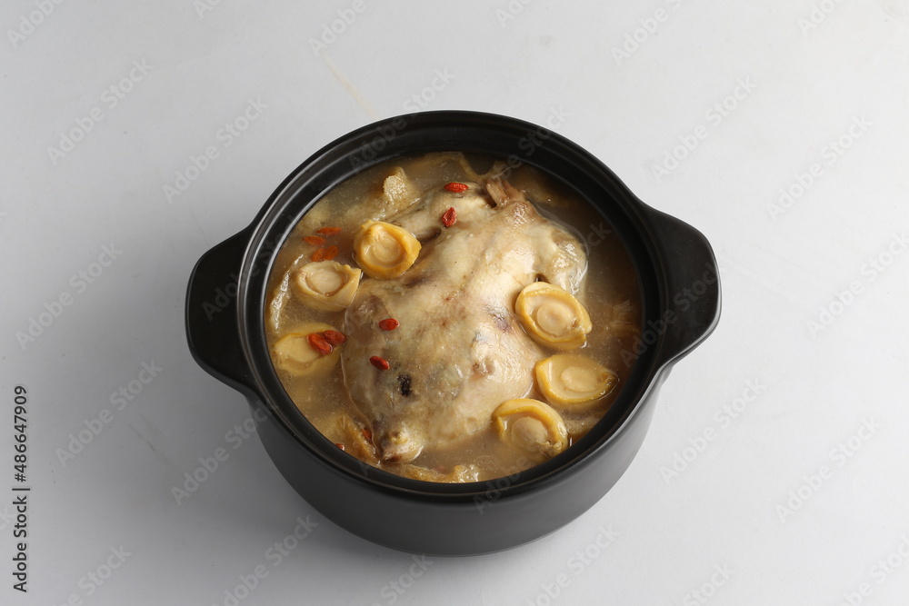 freshly hot stewed whole kampong chicken with abalone seafood in clay pot herbal soup on white background freshly hot stewed whole kampong chicken with abalone seafood in clay pot herbal soup on white background