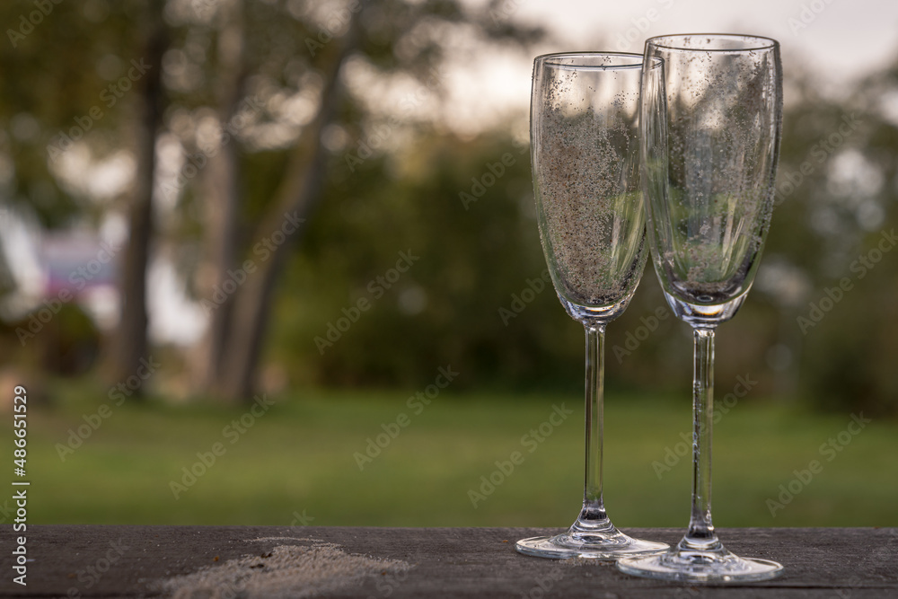 Closeup of two champagne glasses with sand in them, left at a picnic area Closeup of two champagne glasses with sand in them, left at a picnic area