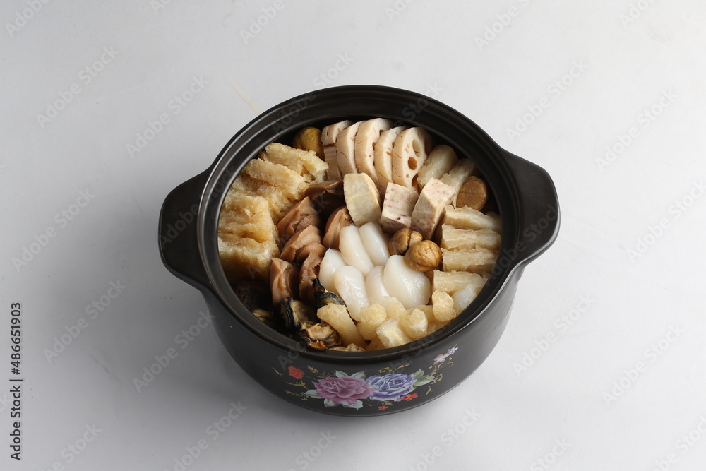 freshly hot stewed Peng cai with seafood and meat in herbal sauce clay pot and yellow cover on white background Chinese traditional menu freshly hot stewed Peng cai with seafood and meat in herbal sauce clay pot and yellow cover on white background Chinese traditional menu