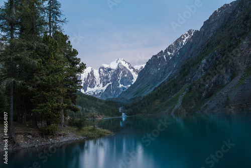 Twilight over a mountain lake among the snow-covered rocks of the forest