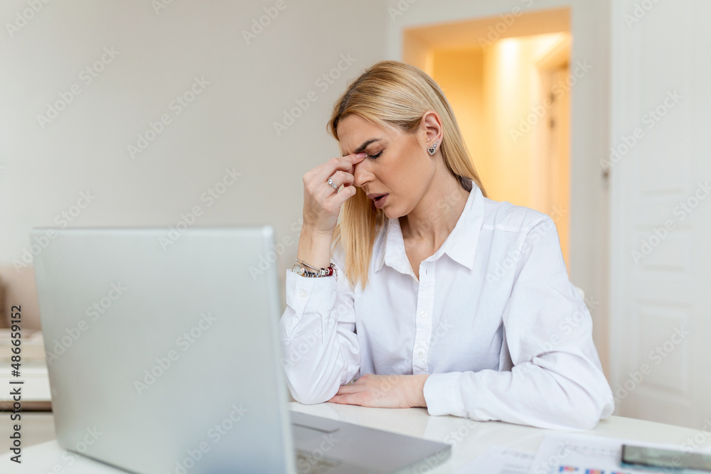 Young frustrated woman working at office desk in front of laptop suffering from chronic daily headaches, treatment online, appointing to a medical consultation, electromagnetic radiation, sick pay Young frustrated woman working at office desk in front of laptop suffering from chronic daily headaches, treatment online, appointing to a medical consultation, electromagnetic radiation, sick pay