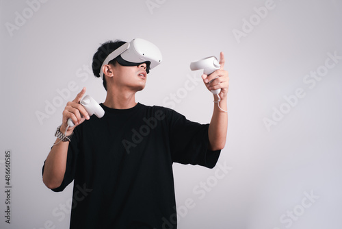 Surprised teen male student use vr glasses and looks at empty space with gray background. Virtual gadgets for entertainment, work, free time and study. Virtual reality metaverse technology concept. photo
