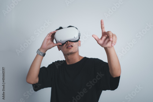 Surprised teen male student use vr glasses and looks at empty space with gray background, studio shot.Virtual gadgets for entertainment, work, free time and study. Virtual reality technology concept.