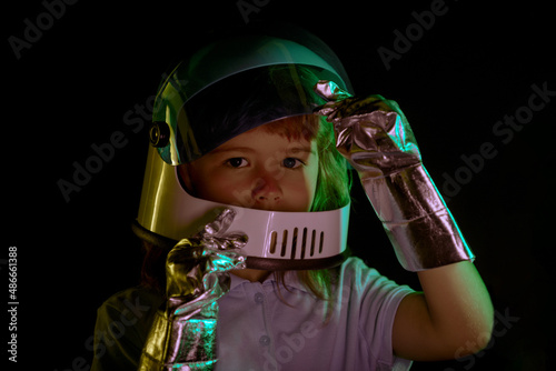 Child boy imagines himself to be an astronaut in an space helmet. Close up kids face on black.