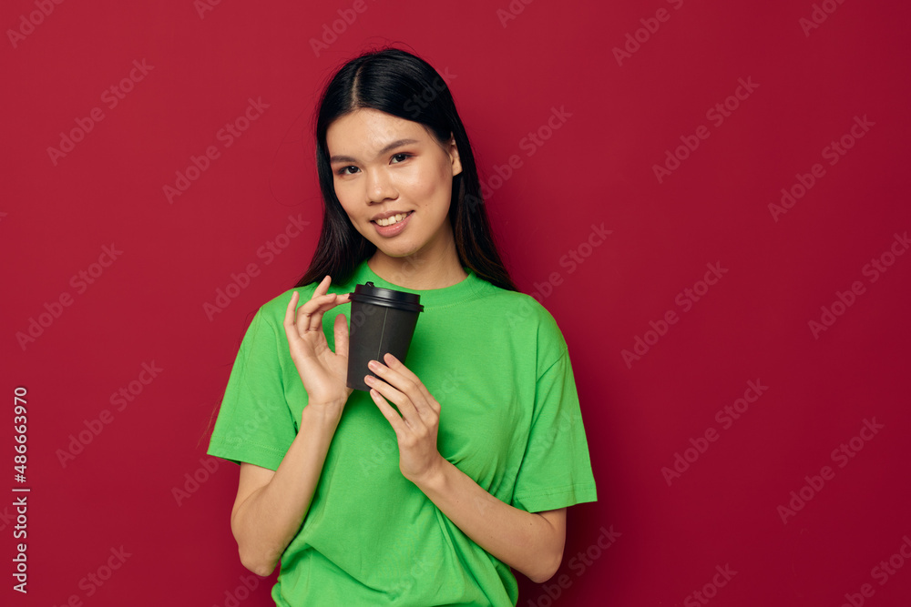 Portrait Asian beautiful young woman smile green t-shirt black disposable cups fashion red background unaltered Portrait Asian beautiful young woman smile green t-shirt black disposable cups fashion red background unaltered