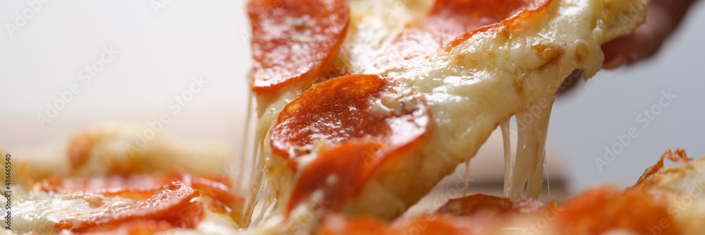 Slice of juicy fresh hot pizza is taken out of box closeup Slice of juicy fresh hot pizza is taken out of box closeup