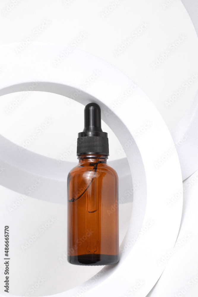 Amber glass dropper bottle on round form on white background. Cosmetic container mock-ups. Background for branding and packaging presentation. Natural skincare beauty product concept