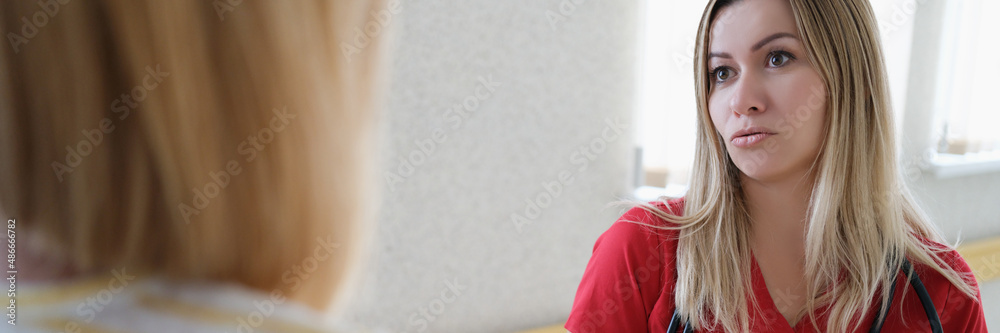 Fototapeta premium Female doctor communicates with patient in bleach corridor