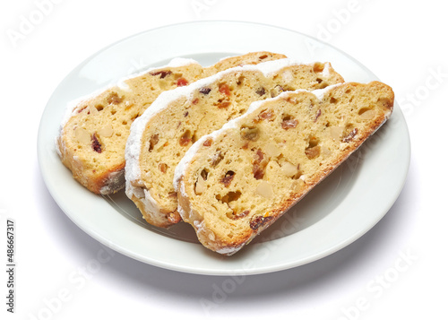 Slices of Traditional Christmas stollen cake with marzipan and dried fruit isolated on white ceramic palte