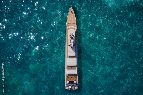 Big yacht for millionaires in the sea drone view. Luxurious white mega yacht on water in the reflection of the sun top view. Big white super ship in the ocean aerial view.