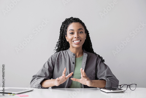 Beautiful business woman looking and speaking through the web camera while making a video conference from office or home.