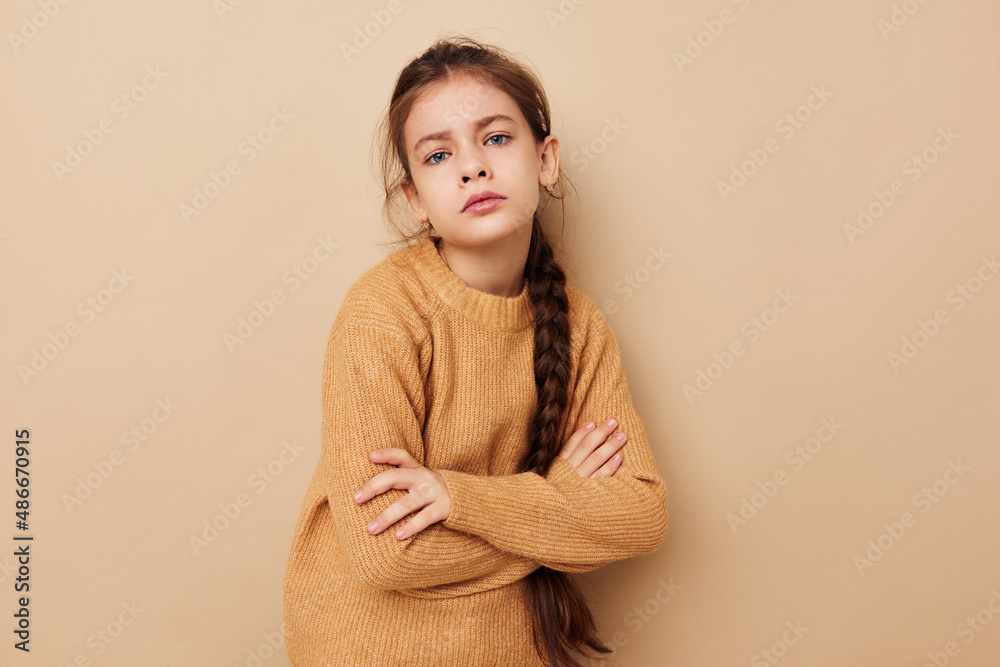 Portrait of happy smiling child girl long pigtail beige sweater grimace beige background Portrait of happy smiling child girl long pigtail beige sweater grimace beige background