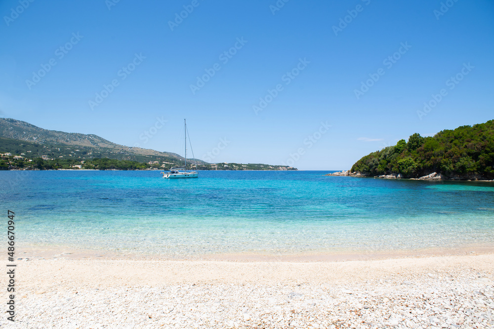 Beautiful beach with sailing boat, Corfu island, Greece, Picturesque mediterranean landscape, famous travel destination in Europe.