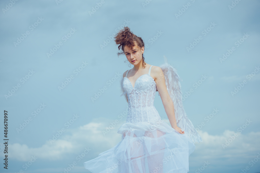 Valentines Day. Love and romance. Teenager angel girl with wings, copy space on sky.