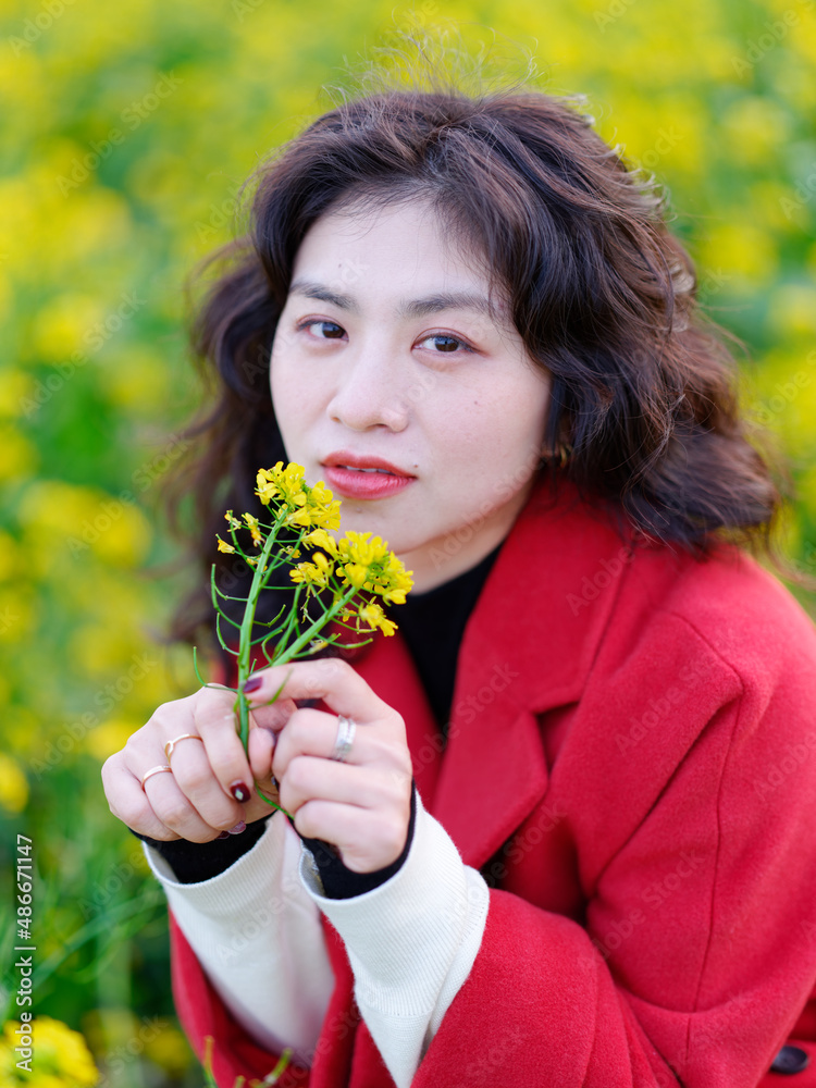 A Chinese woman dressed in red stands in a field of rape flowers A Chinese woman dressed in red stands in a field of rape flowers