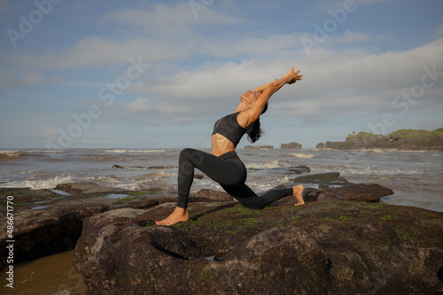 Morning beach yoga. Asian woman practicing Anjaneyasana. Low Lunge. Crescent Moon Pose. Equestrian Pose. Lunging back bending asana. Flexible healthy body. Yoga retreat. Mengening beach, Bali