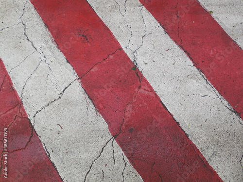 Wide red and white bright stripes on the old wet cracked asphalt. Stop sign for special vehicles (ambulance, fire service, police, etc.).