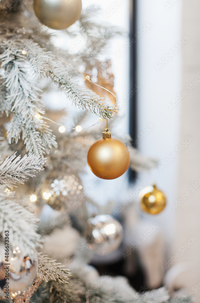 gold ball bauble ornament on christmas tree closeup background. white silver and gold color palette. christmas tree closeup backgroundю