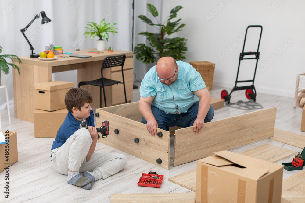 Father tries on the furniture boards to see if they fit together. Father tries on the furniture boards to see if they fit together.